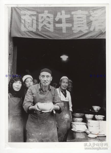 1980年，甘肃兰州，一家清真牛肉面店门口，店主端着一碗拉面，让拍摄者品尝当地特色小吃：兰州拉面。