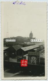 民国北京正阳门火车站西侧的大楼上向东北方向拍摄正阳门站，可见其南侧的车站月台与停靠车辆，有无敌牌牙膏，盛锡福时帽莊等广告牌，照片左侧的美国军营的通讯铁塔。11X6.5厘米